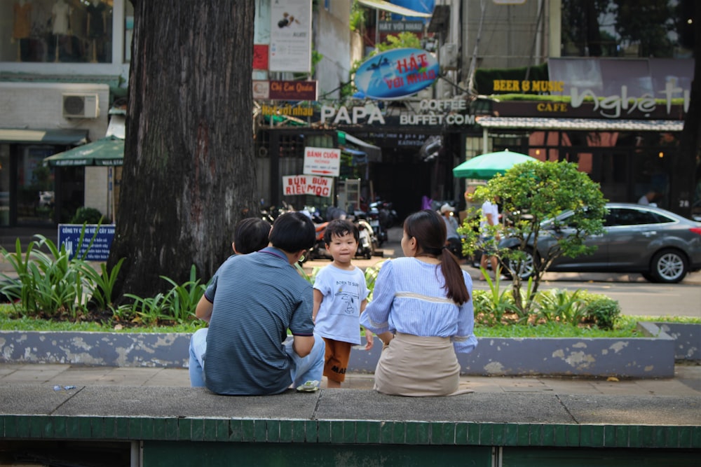 people sitting on green bench near road during daytime