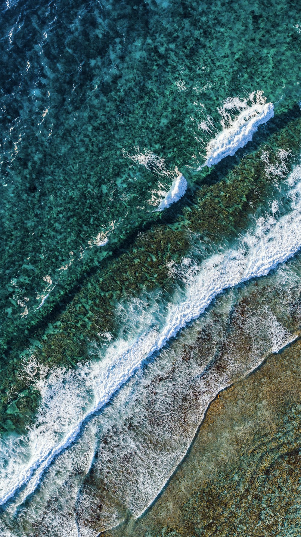 Vista aérea de las olas verdes y blancas del océano durante el día