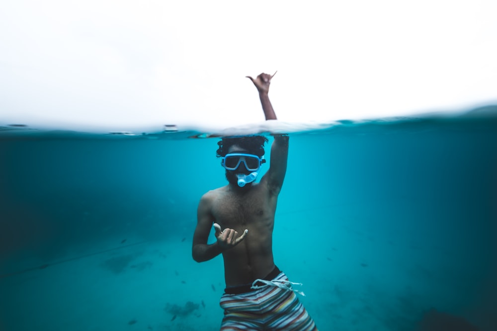 man in white and black stripe shorts wearing goggles in water