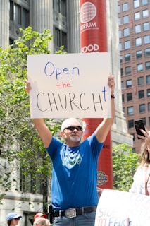 man in blue crew neck t-shirt holding white and red signage