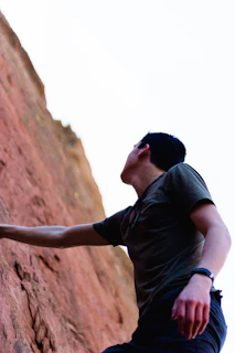A climber stretching their fingers on a rocky outcrop at sunrise.