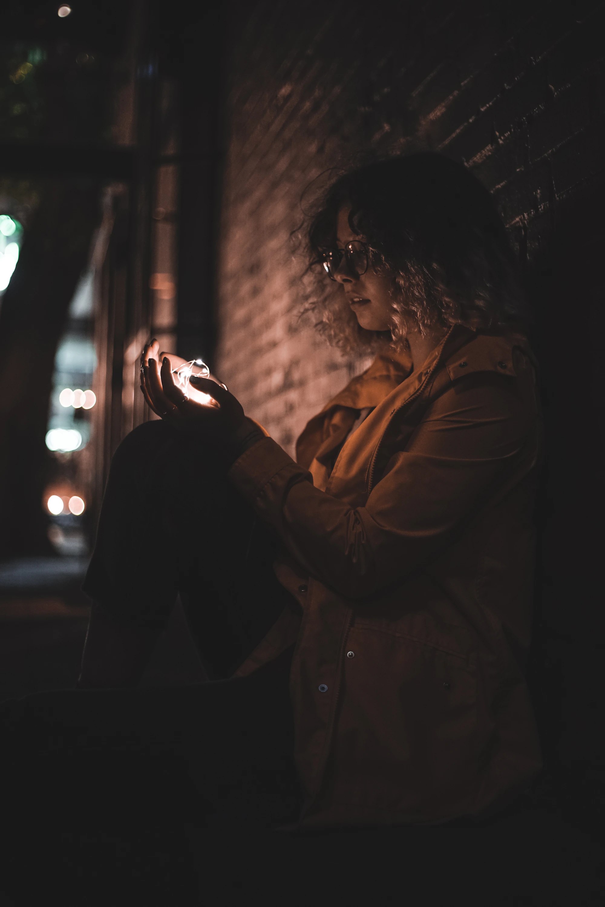 Mulher segurando uma luz nas mãos, à noite