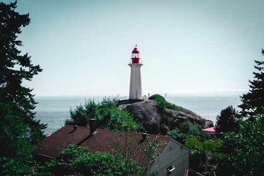 white and red lighthouse near body of water during daytime in Lighthouse Park | West Vancouver Canada