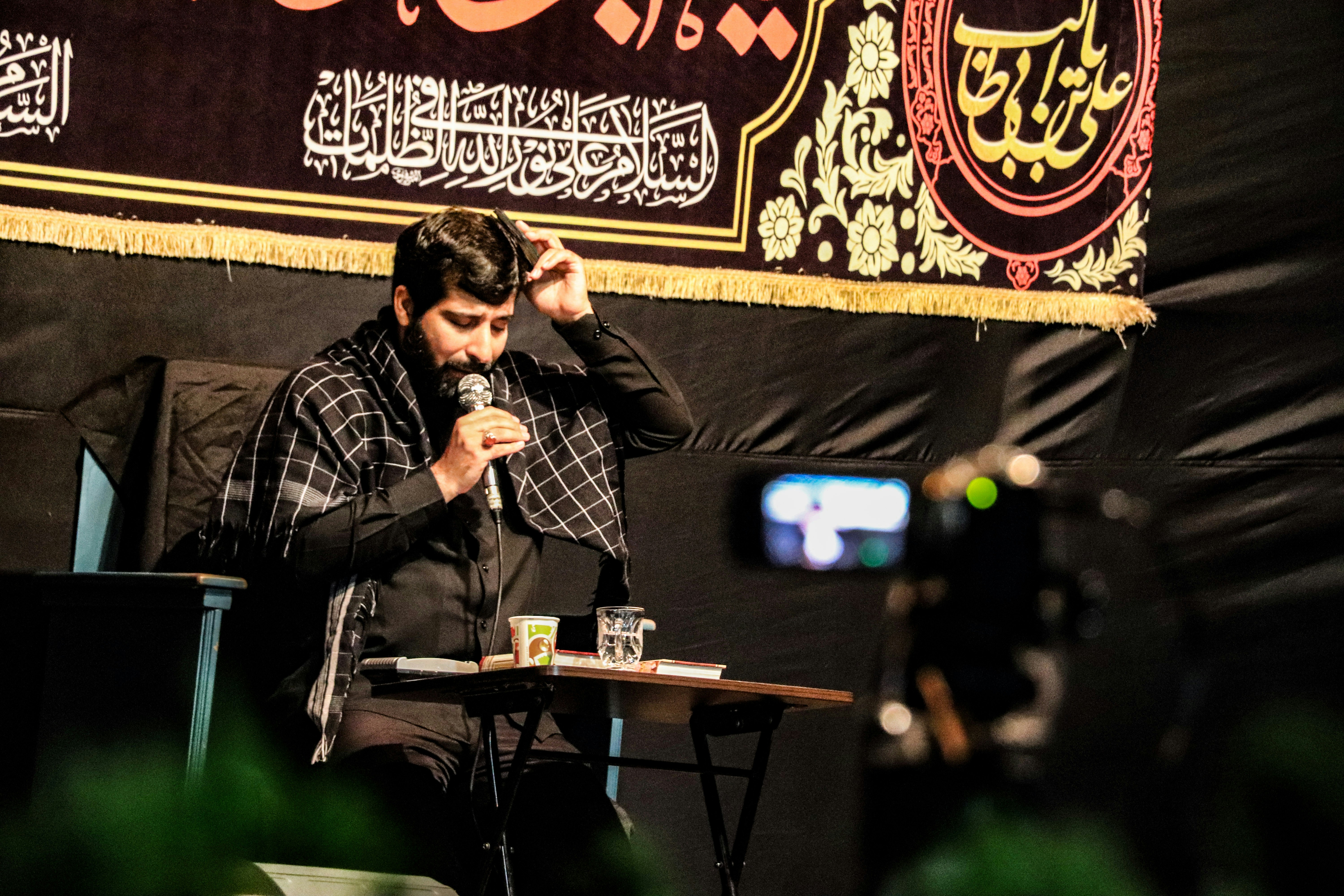 man in black and white plaid dress shirt standing and singing