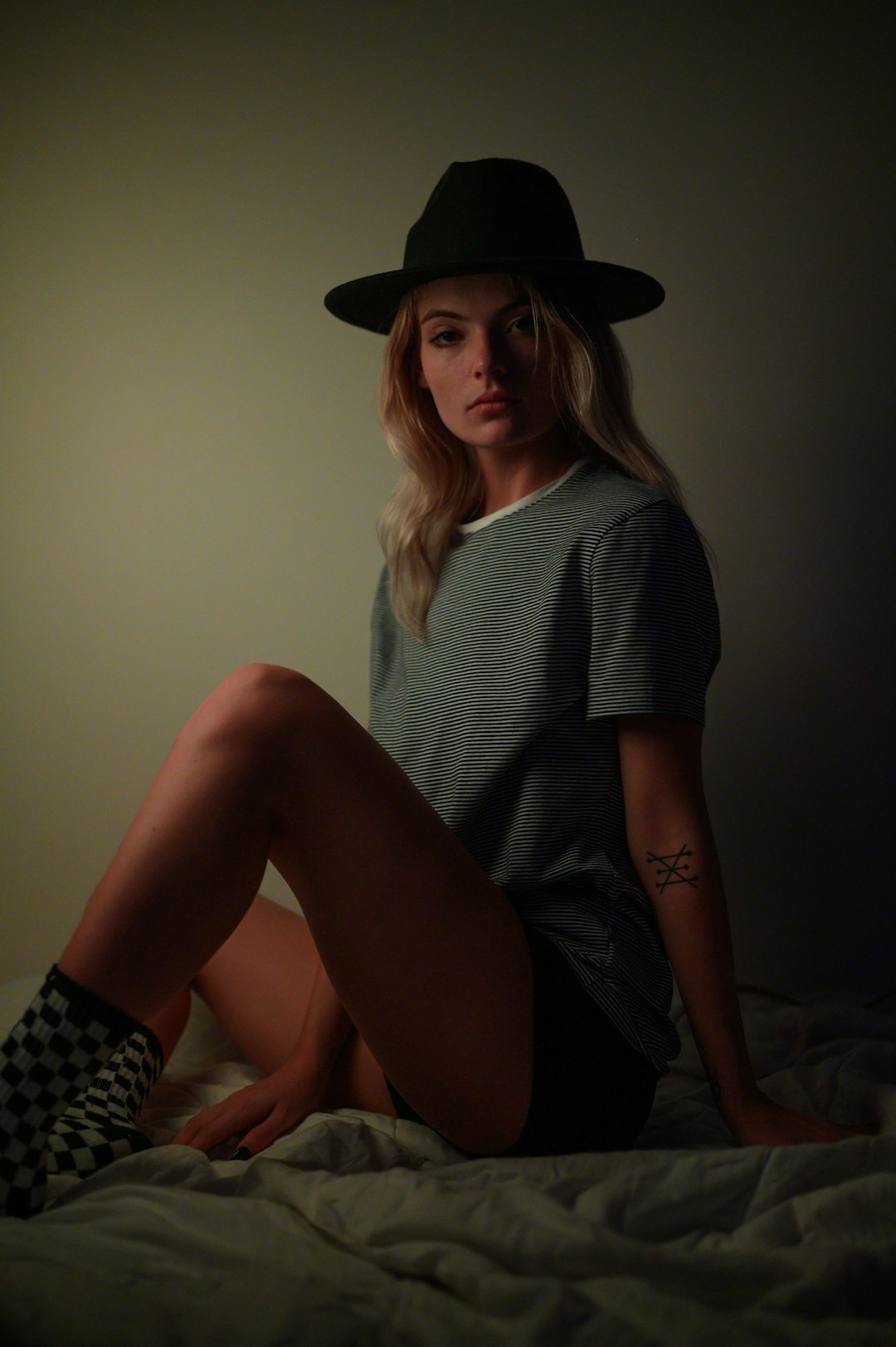 woman in black and white stripe shirt and black hat sitting on brown wooden seat