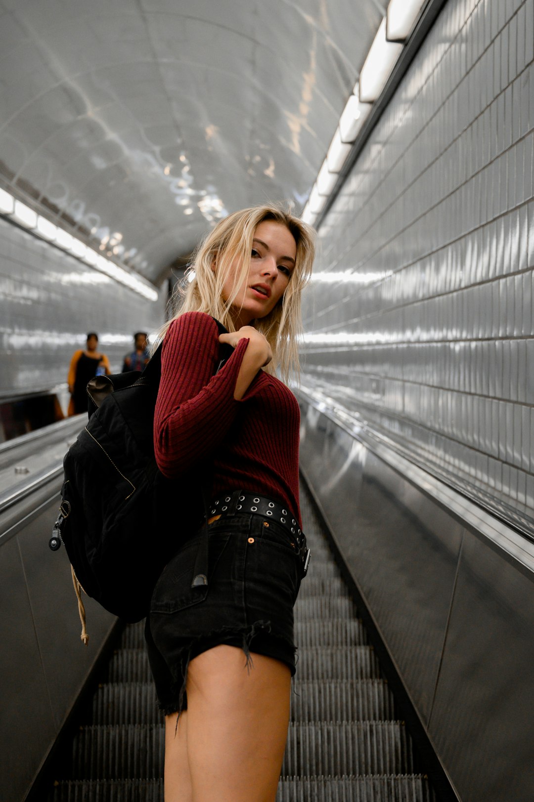 woman in red knit sweater and black denim jeans standing on train station