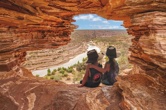 woman in black tank top and black shorts sitting on brown rock formation during daytime in Kalbarri National Park WA Australia