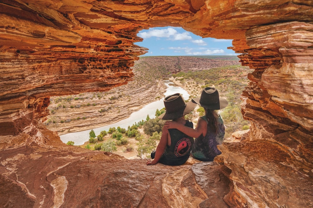 woman in black tank top and black shorts sitting on brown rock formation during daytime