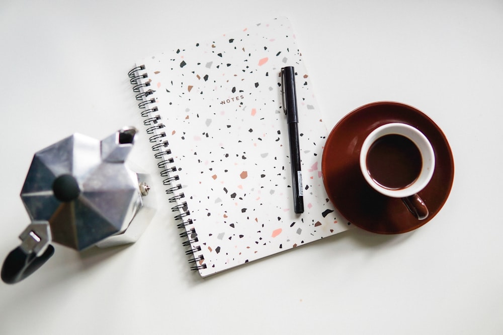 red ceramic mug on white notebook