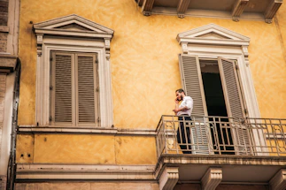 Friendly property manager talking on phone by a home exterior.