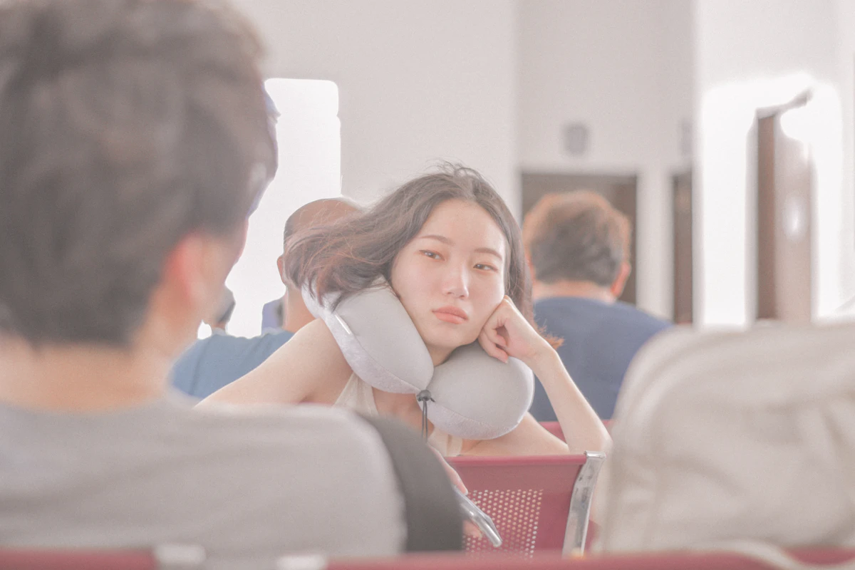 Traveler resting on a plane wearing a grey neck pillow