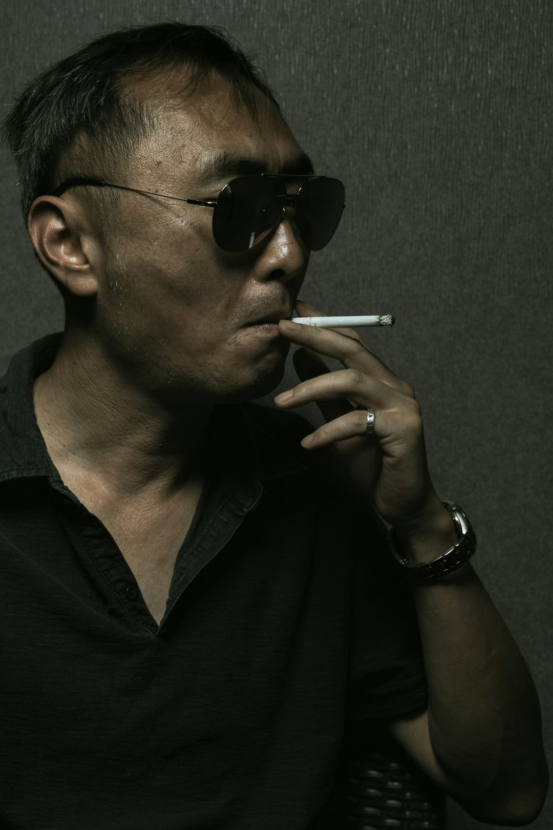 man in black polo shirt smoking