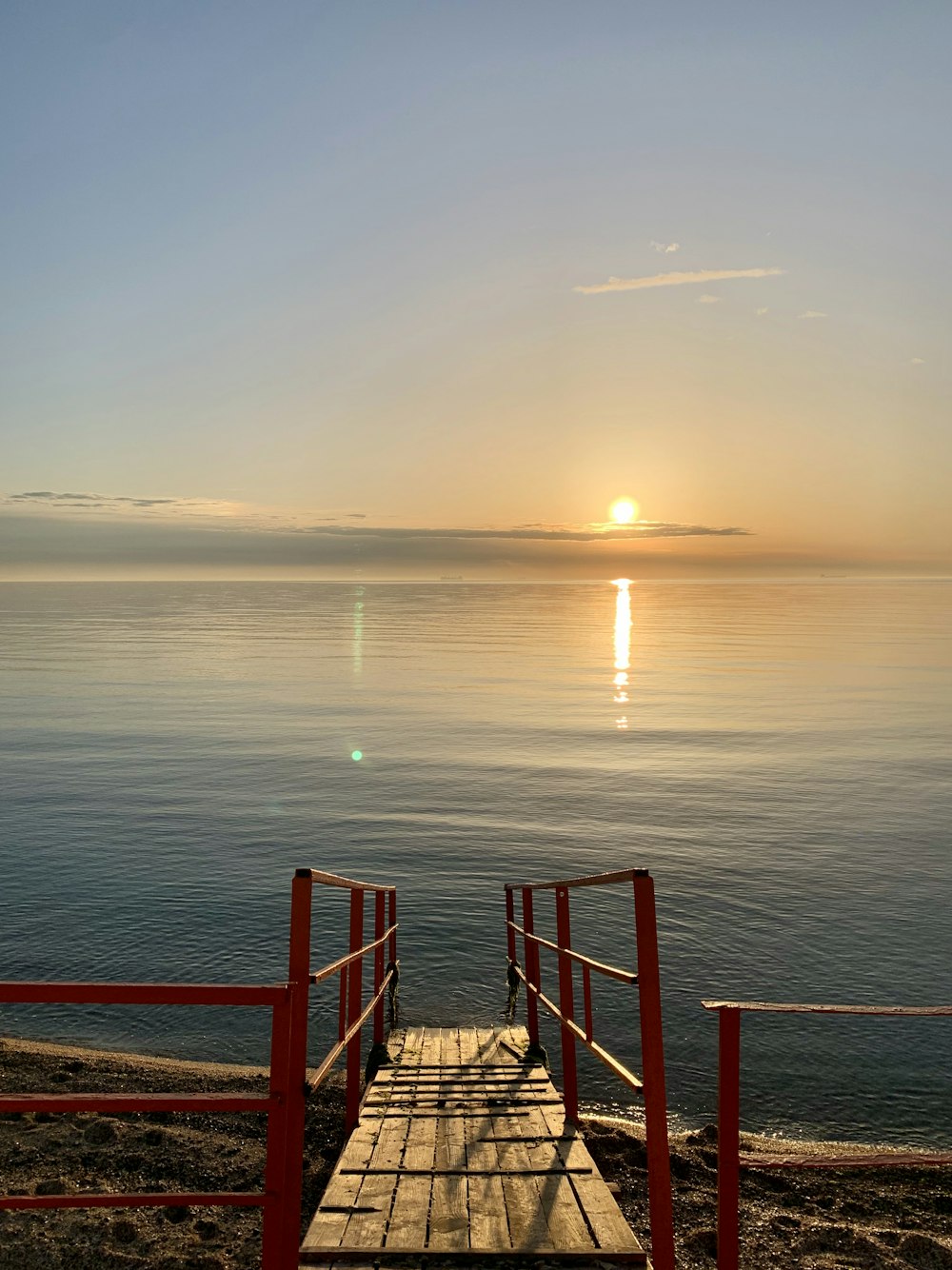 brown wooden fence on sea during sunset