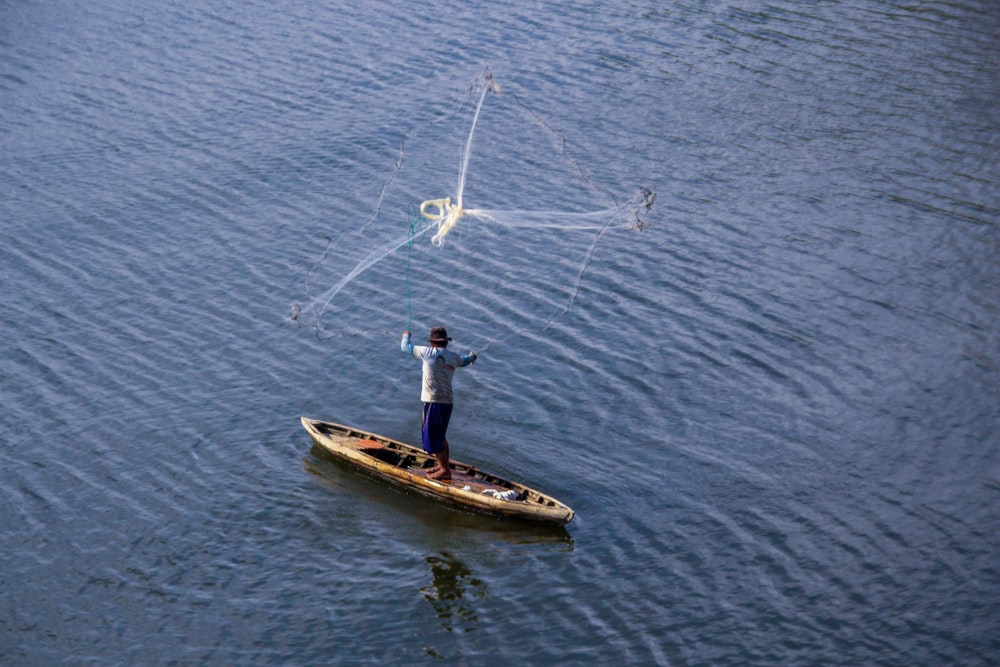 man in blue shirt and black pants riding on white and brown boat on body of on on on on