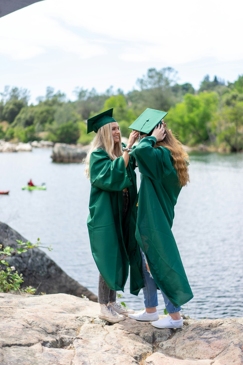 woman in green academic dress and black mortar board standing on brown wooden log during daytime