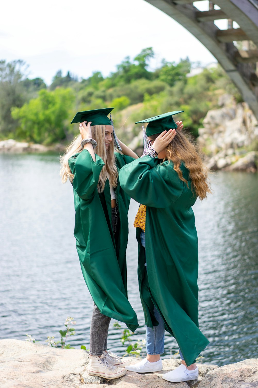 woman in green academic dress and black mortar board standing on river during daytime