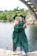 woman in green academic dress standing on gray concrete pavement during daytime