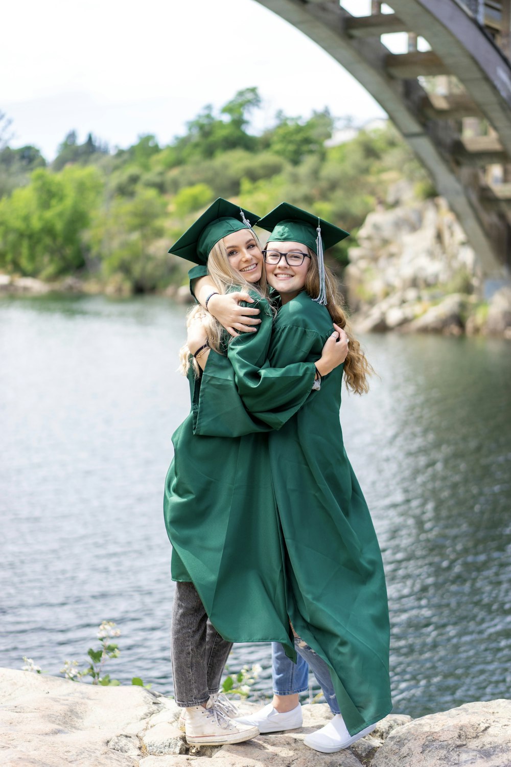 woman in green academic dress standing on gray concrete pavement during daytime