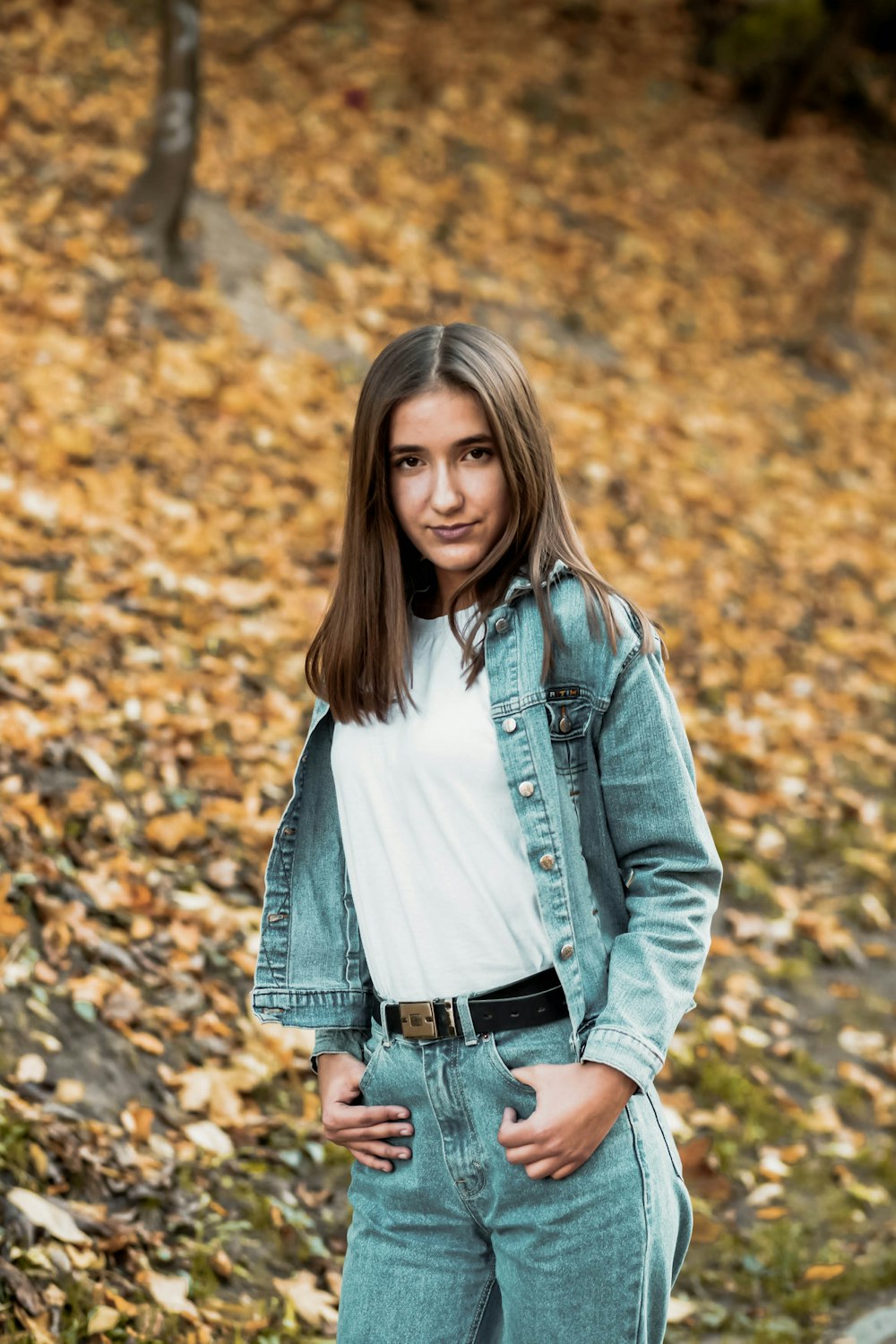 woman in blue denim jacket standing on dried leaves during daytime
