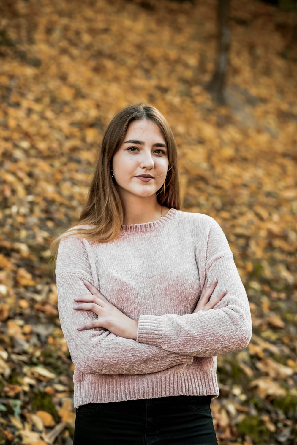 woman in gray sweater standing on brown leaves during daytime
