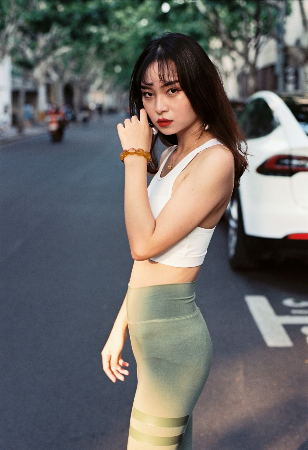 woman in white tank top and gray leggings standing on road during daytime