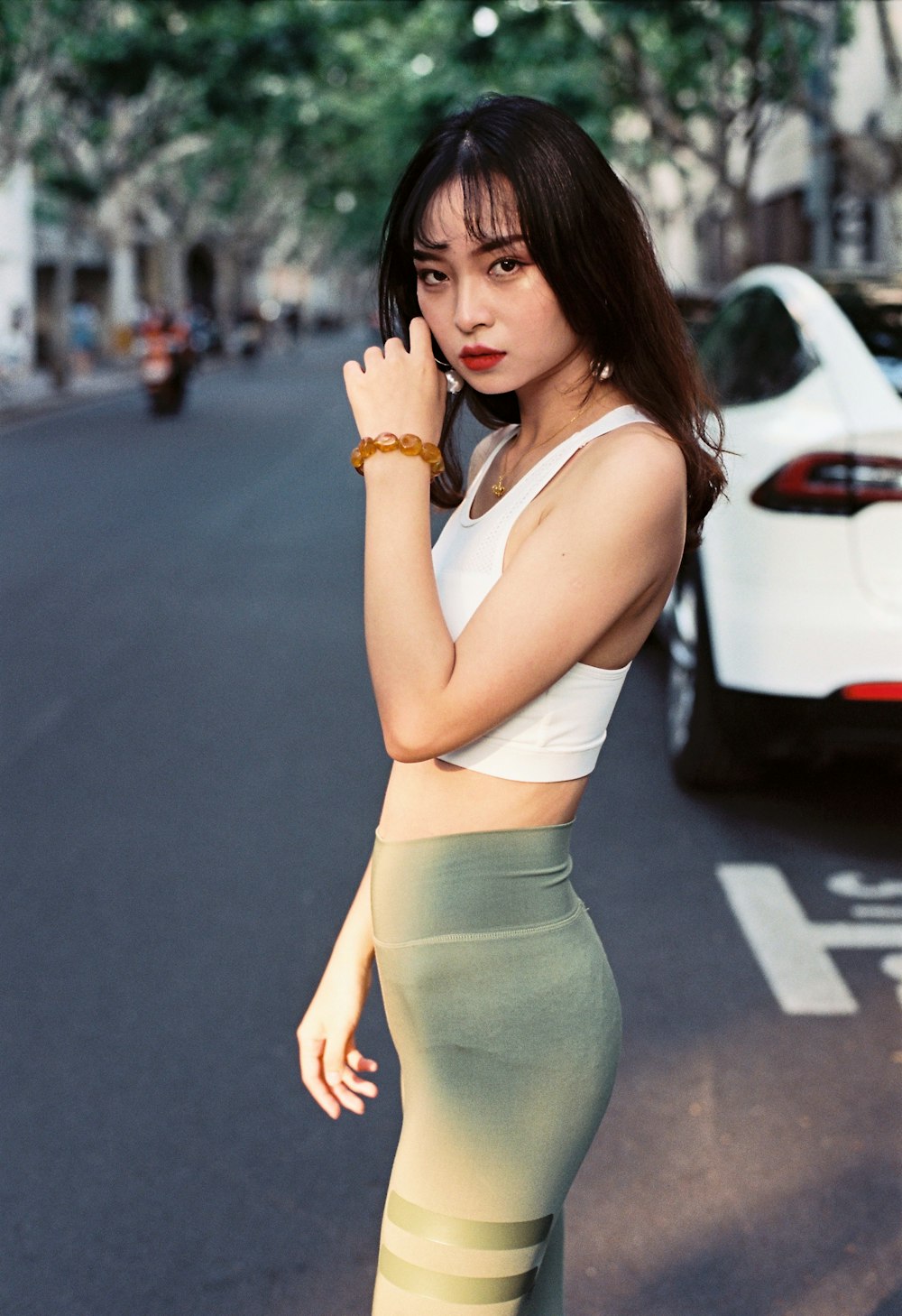 woman in white tank top and gray leggings standing on road during daytime