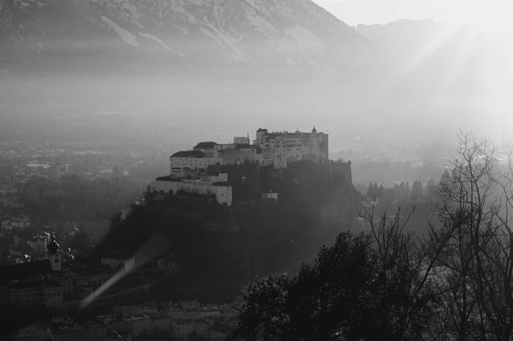 grayscale photo of castle on top of mountain