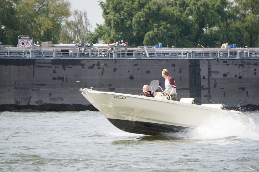 Mann im weißen Hemd fährt tagsüber ein weißes und schwarzes Motorboot
