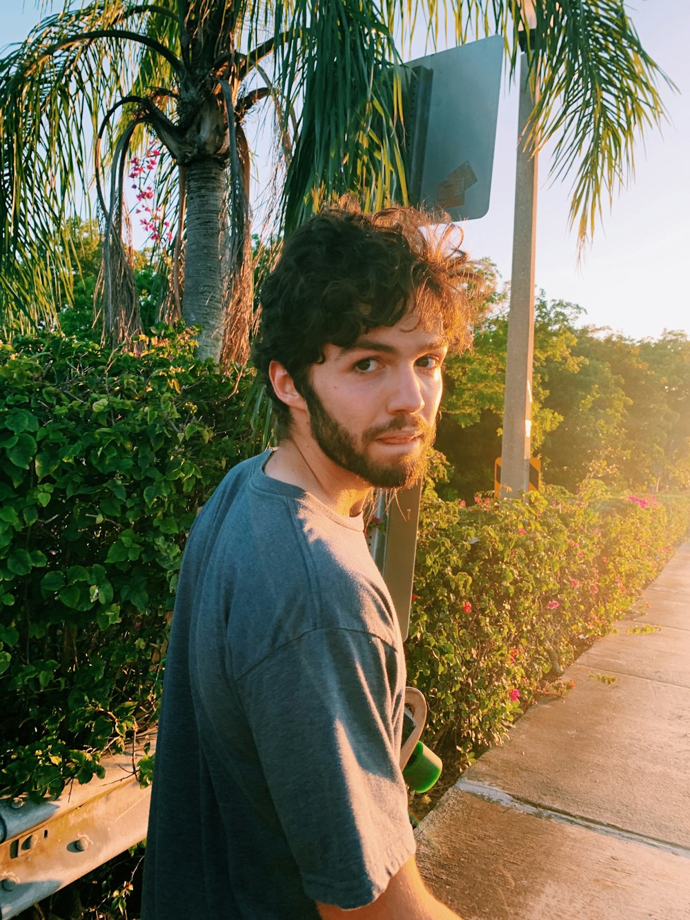 man in blue crew neck shirt standing near green plants during daytime