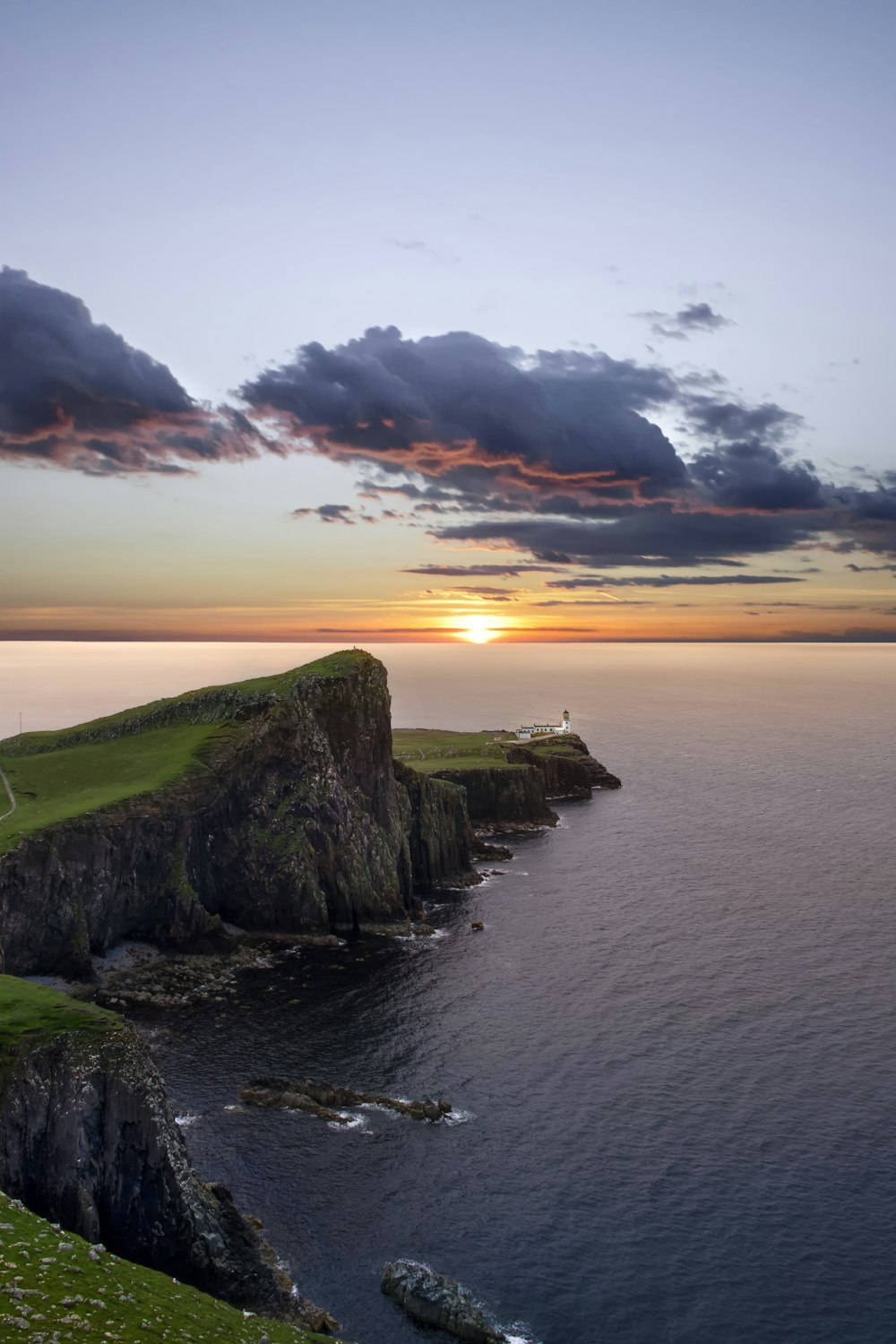 green and black mountain beside sea during sunset