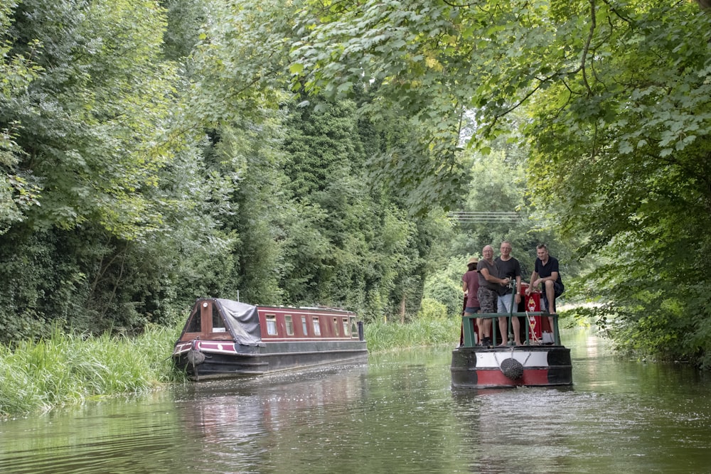 people riding red boat on river during daytime