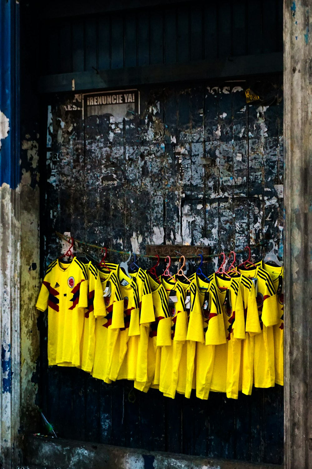 grupo de hombres con camisa de manga larga amarilla y negra de pie junto a una pared de hormigón marrón