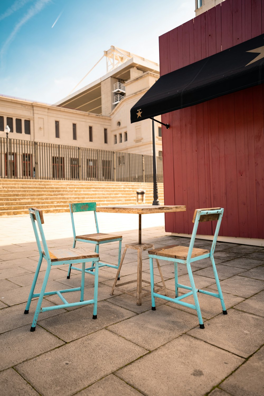 brown wooden table and chairs near red wooden building during daytime
