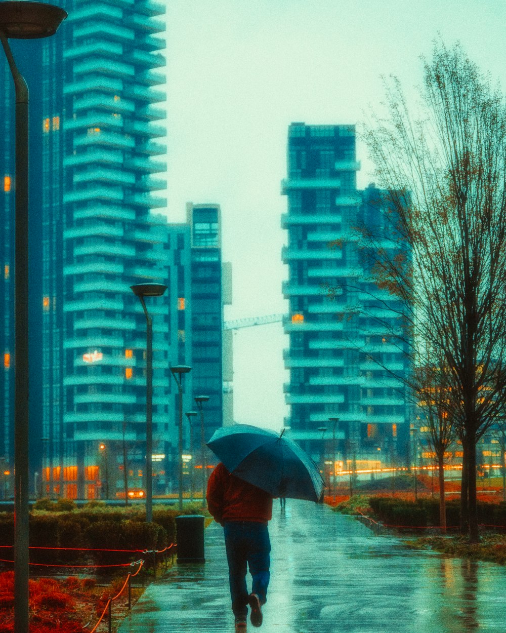 person in black jacket holding umbrella standing on sidewalk during daytime