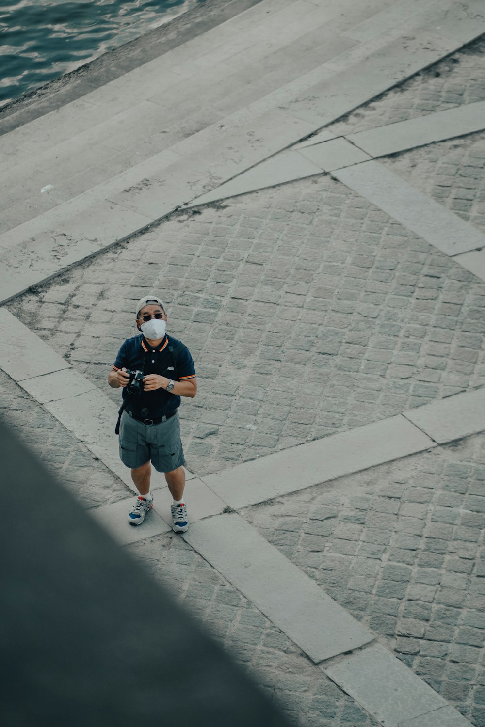 Garçon en T-shirt noir et jean bleu debout sur le trottoir en béton gris pendant la journée