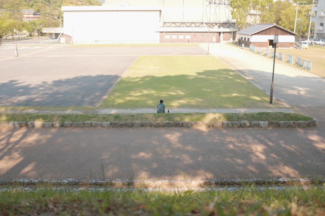 person in black jacket sitting on green grass field during daytime