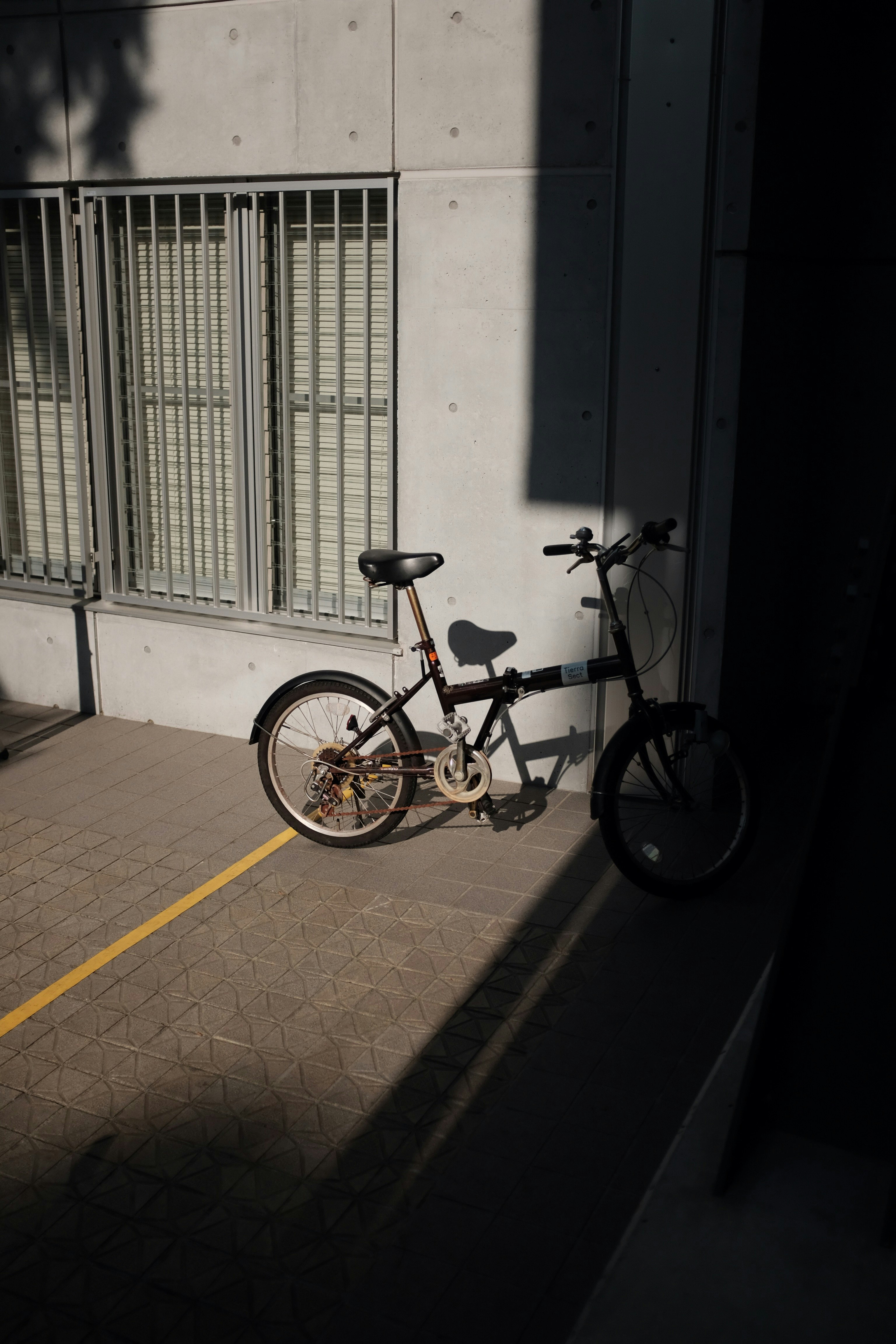 yellow and black bicycle parked beside white concrete wall