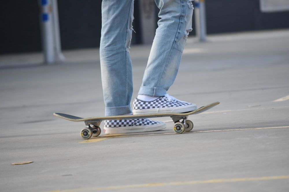 person in blue denim jeans and white sneakers riding skateboard