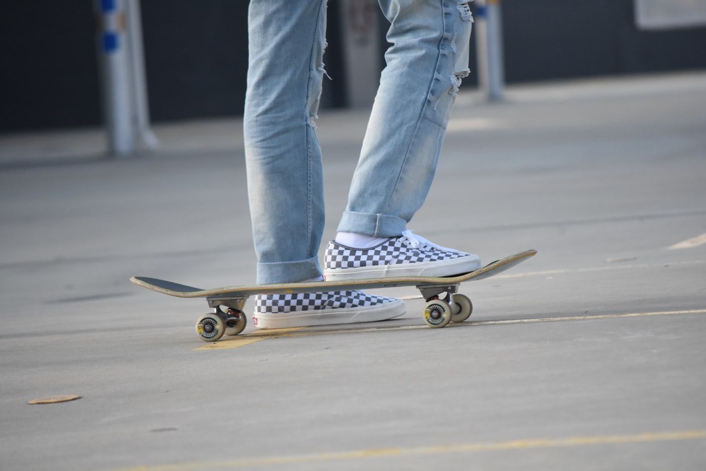 Skater standing on a skateboard wearing checkerboard slip-on shoes