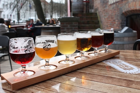 clear drinking glasses with beer on brown wooden table