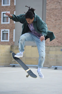 A candid shot of a skateboarder mid-trick, the type of pose logo visible on their jacket sleeve.