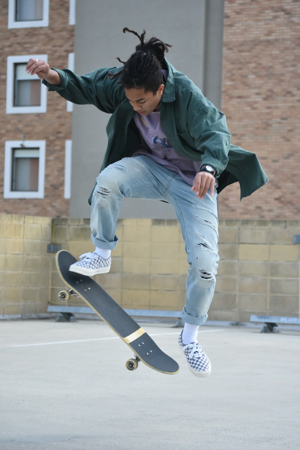 homme en sweat à capuche vert et jean en denim bleu assis sur une planche à roulettes pendant la journée