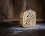 Close-up of artisan bread loaf with a dusting of flour on a dark wooden table.