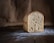 A warm loaf of freshly baked bread resting on a rustic wooden table, surrounded by a few scattered flour dust and baking tools.
