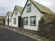 A container house with slate gray exterior blending into a mountain landscape under clear blue sky.