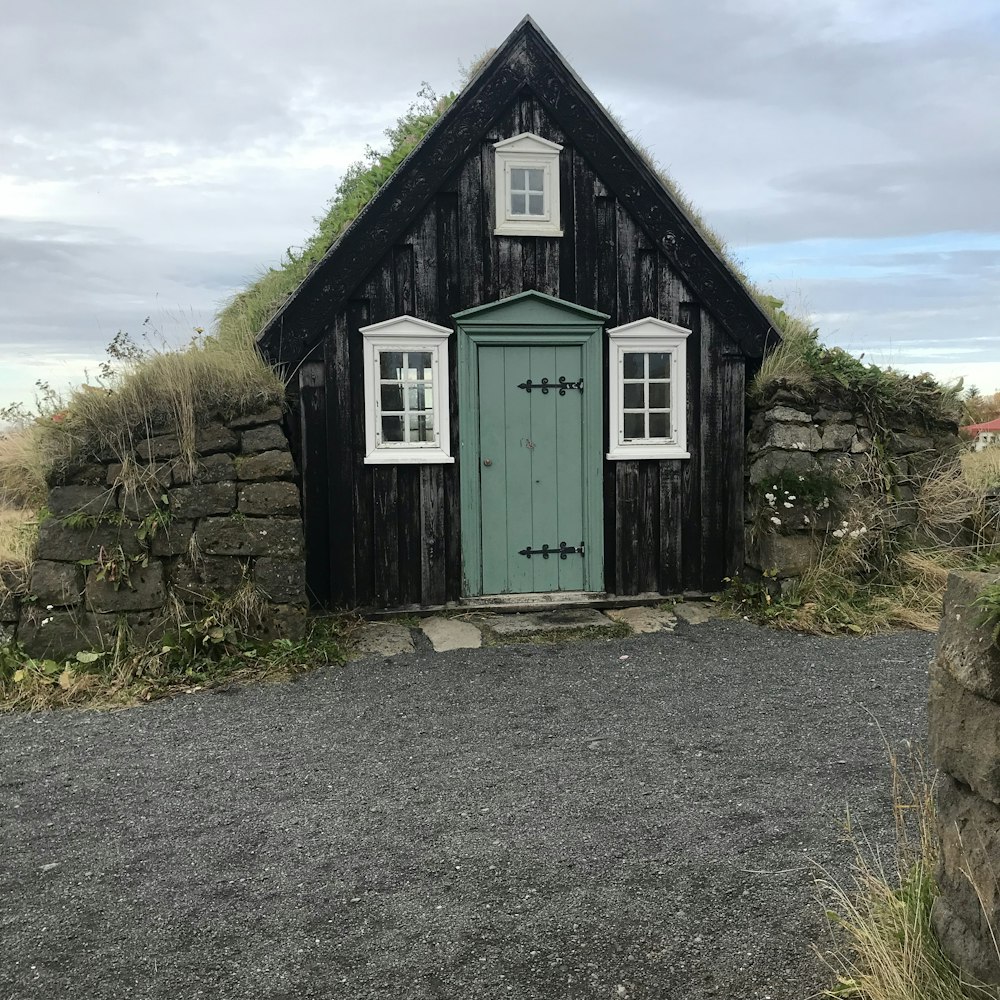 green wooden house on green grass field under white clouds during daytime