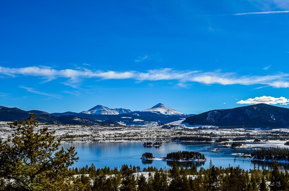 montagna innevata vicino al lago sotto il cielo blu durante il giorno