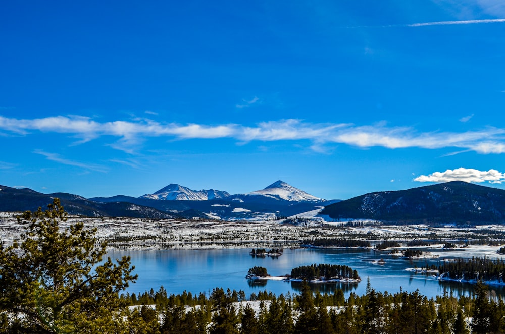 snow covered mountain near lake under blue sky during daytime