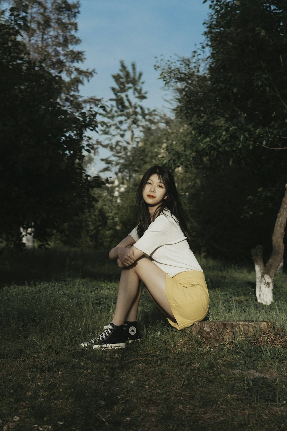 a woman sitting in the grass with her legs crossed