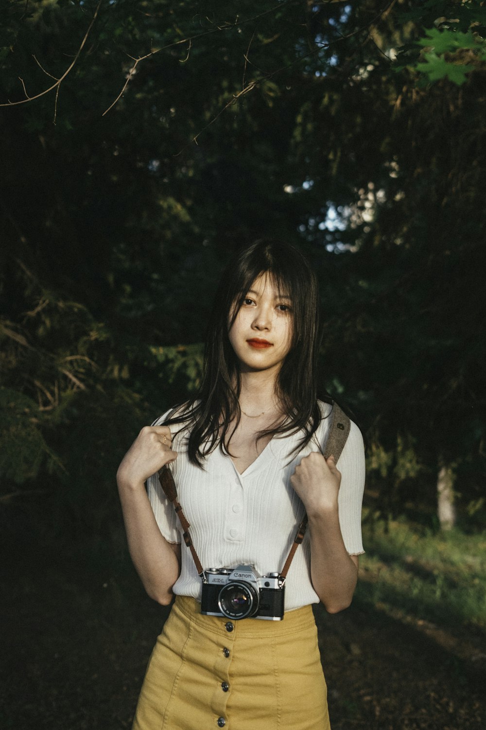 woman in white tank top holding black dslr camera